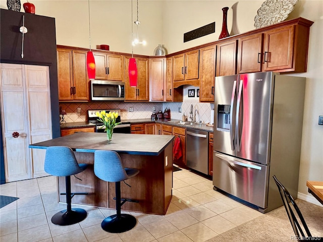 kitchen with appliances with stainless steel finishes, a center island, brown cabinetry, and tasteful backsplash