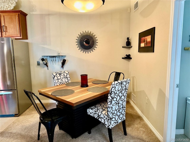 dining area featuring baseboards, visible vents, and light colored carpet