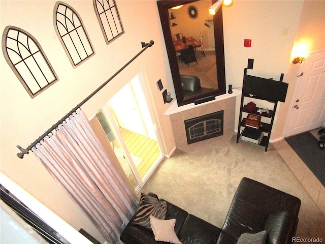 carpeted living area with a tile fireplace and baseboards