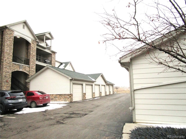 view of home's exterior featuring stone siding and community garages