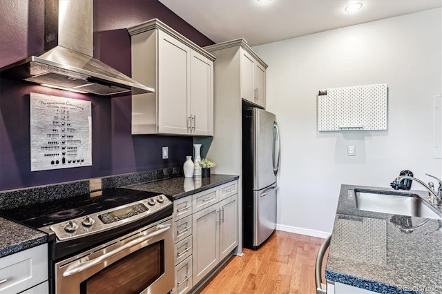 2958 Syracuse St Unit 214, Denver, CO 80238 - kitchen featuring appliances with stainless steel finishes, wall chimney exhaust hood, a sink, baseboards, and light wood-style flooring