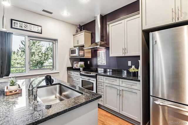 2958 Syracuse St Unit 214, Denver, CO 80238 - kitchen featuring wall chimney range hood, a sink, stainless steel appliances, light wood-type flooring, and visible vents