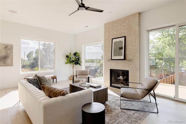 living room featuring a large fireplace, ceiling fan, and light hardwood / wood-style flooring