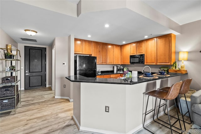 kitchen featuring black appliances, dark countertops, a peninsula, and visible vents