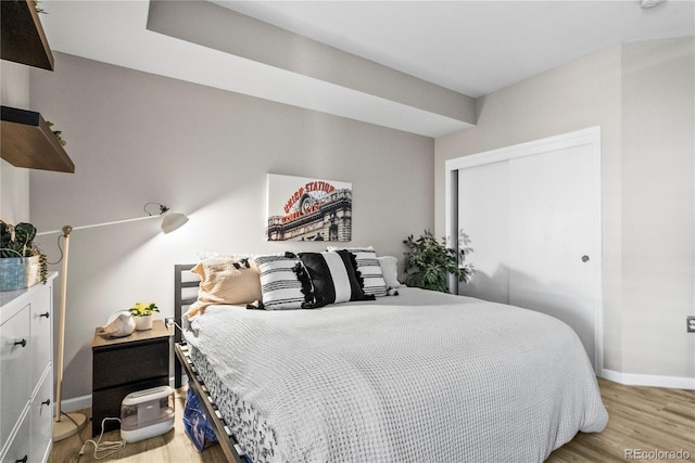 bedroom with a closet, light wood-style flooring, and baseboards