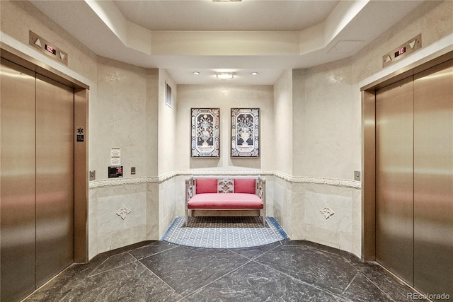 corridor featuring tile walls, elevator, and a wainscoted wall