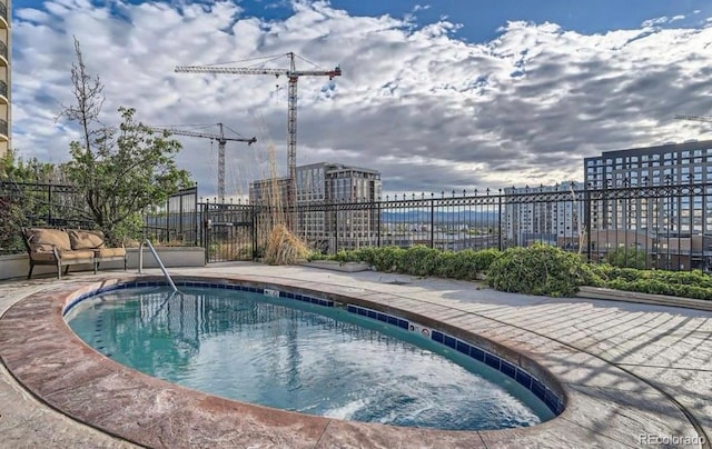 view of swimming pool with a patio area, a pool, and a view of city