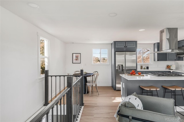 kitchen featuring stainless steel appliances, gray cabinets, island range hood, and light wood-type flooring