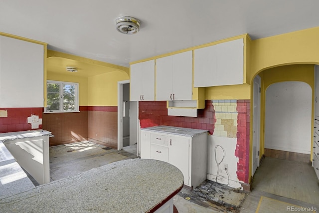 kitchen with white cabinets, light wood-type flooring, and tile walls