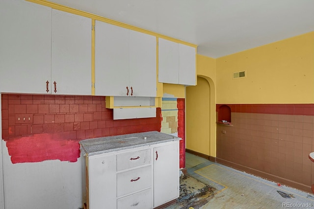 kitchen with tile walls and white cabinets