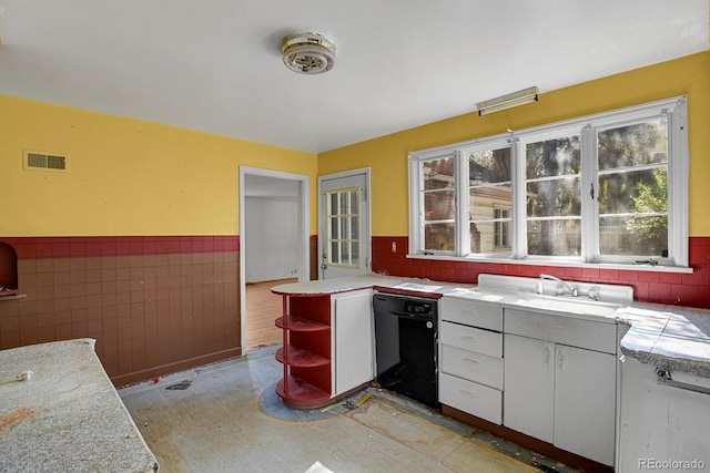 kitchen featuring light stone countertops, white cabinets, sink, tile walls, and kitchen peninsula