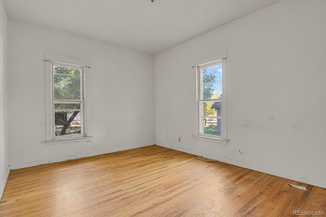 empty room featuring light wood-type flooring and a healthy amount of sunlight