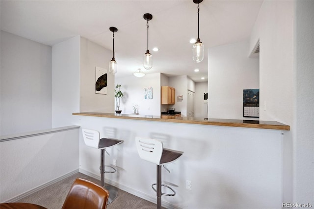 920 S Locust St Unit E, Denver, CO 80224 - kitchen featuring carpet floors, a breakfast bar, light brown cabinetry, pendant lighting, and recessed lighting