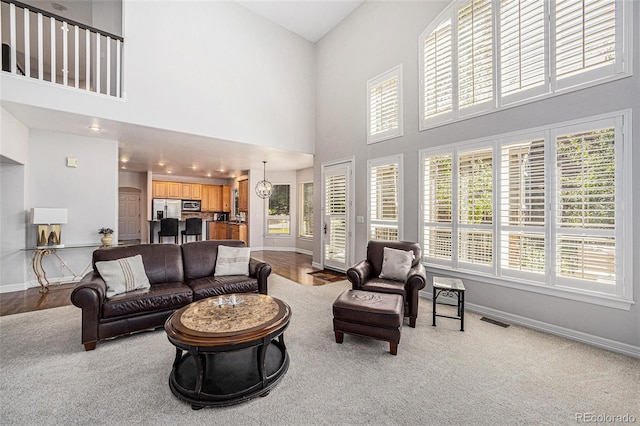 carpeted living room with a high ceiling and a chandelier