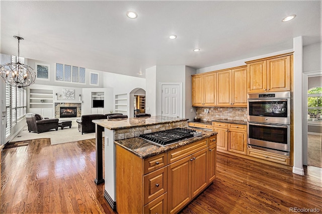 kitchen with stainless steel appliances, an inviting chandelier, dark hardwood / wood-style floors, a kitchen island, and hanging light fixtures