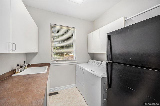 clothes washing area featuring cabinets, sink, and washer and dryer