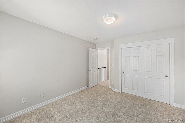 unfurnished bedroom with light carpet and a closet