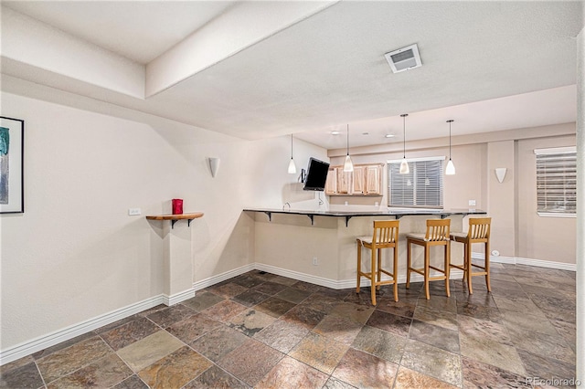 kitchen featuring decorative light fixtures, a kitchen bar, and kitchen peninsula