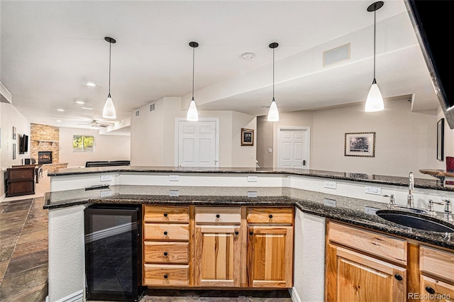 kitchen with a fireplace, beverage cooler, decorative light fixtures, and sink