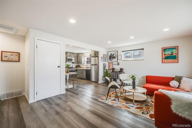 living room featuring recessed lighting, visible vents, baseboards, and wood finished floors