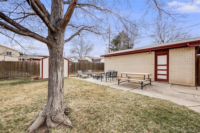 view of yard featuring a shed, an outdoor fire pit, a fenced backyard, a patio area, and an outbuilding