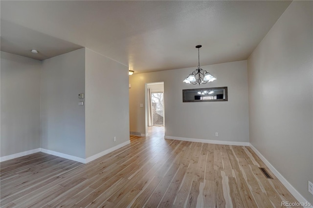 unfurnished room with light hardwood / wood-style floors and a chandelier