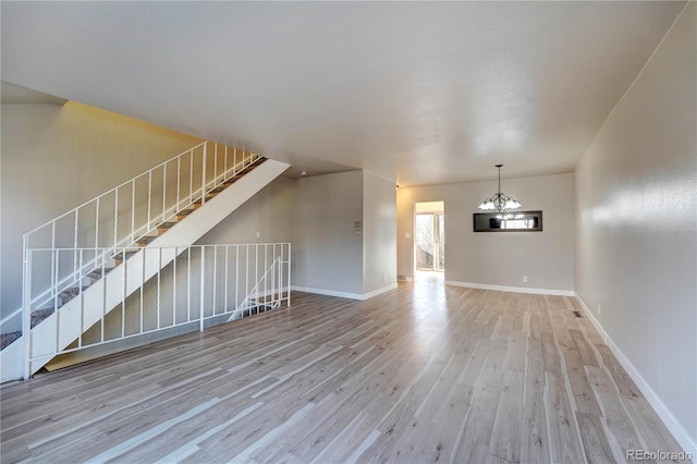 unfurnished living room with light wood-type flooring and a chandelier