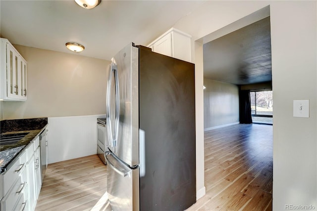 kitchen featuring white cabinets, light hardwood / wood-style floors, dark stone countertops, and stainless steel appliances