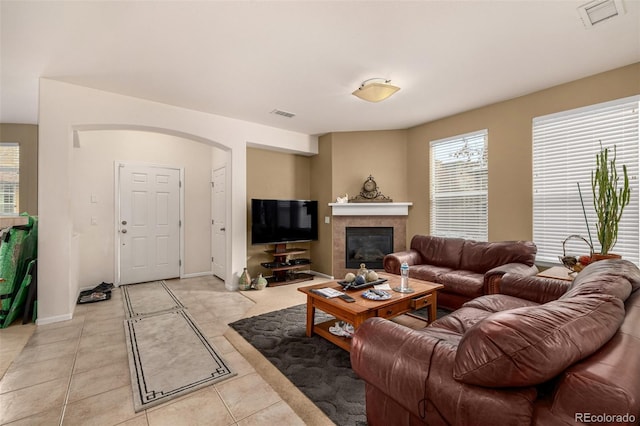 living area featuring light tile patterned floors, a tile fireplace, visible vents, and baseboards