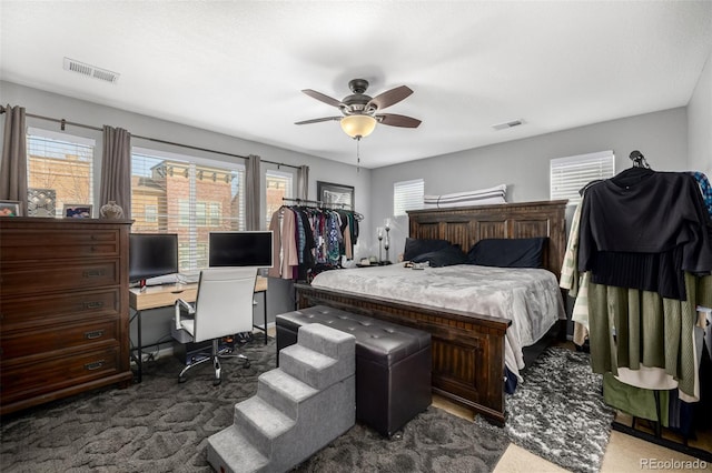 carpeted bedroom featuring ceiling fan, multiple windows, and visible vents