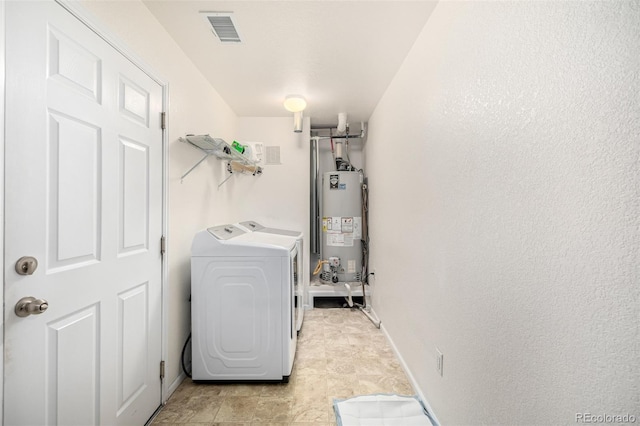 laundry room with laundry area, visible vents, baseboards, water heater, and independent washer and dryer