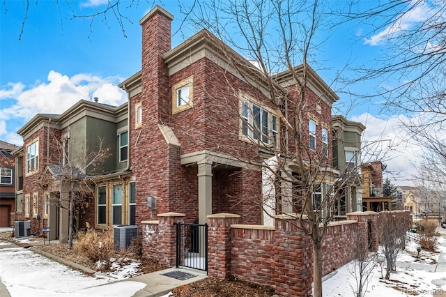 snow covered property with a fenced front yard and cooling unit