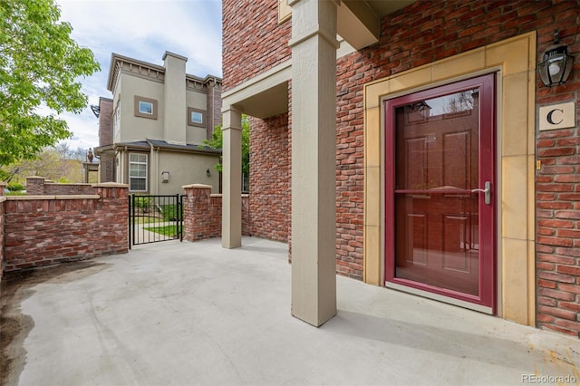 view of exterior entry featuring brick siding and a gate