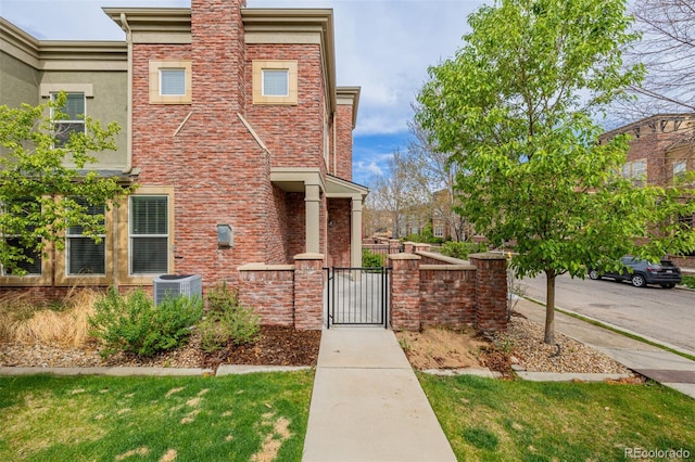 view of front facade featuring brick siding, fence, a gate, and cooling unit