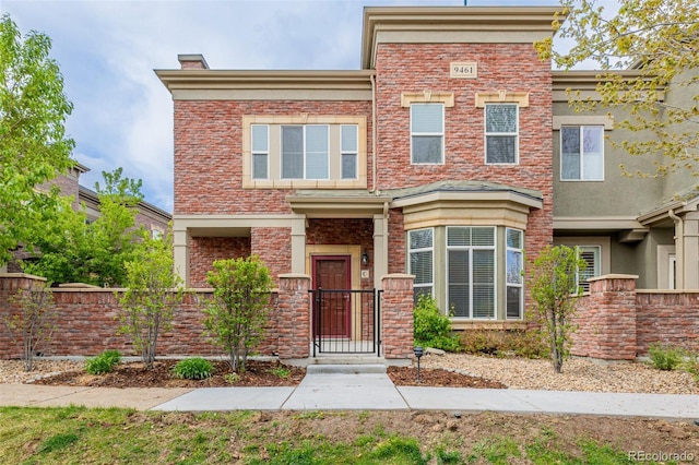 townhome / multi-family property with a fenced front yard, a gate, and stucco siding