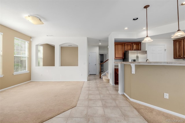 kitchen featuring pendant lighting, light countertops, stainless steel fridge with ice dispenser, baseboards, and light carpet