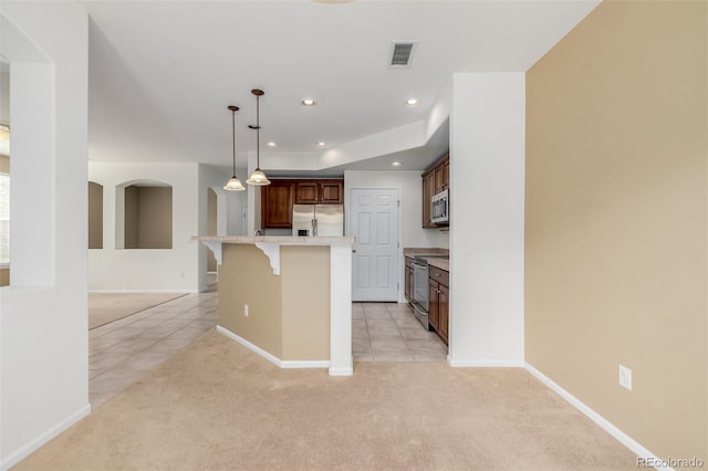 kitchen with visible vents, light carpet, a breakfast bar, light countertops, and appliances with stainless steel finishes