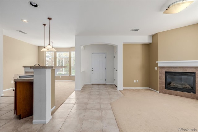 interior space featuring light tile patterned floors, baseboards, light carpet, and visible vents