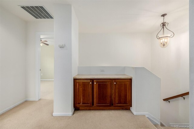 hallway with baseboards, a notable chandelier, light colored carpet, and visible vents