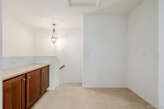 interior space with baseboards, decorative light fixtures, and light colored carpet