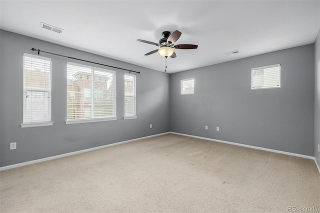 empty room with baseboards, ceiling fan, and light colored carpet