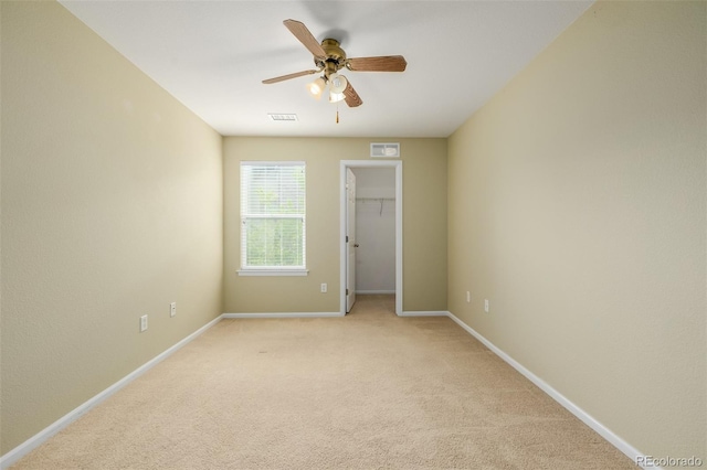 spare room with baseboards, ceiling fan, light colored carpet, and visible vents