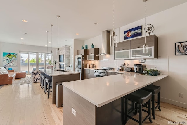3632 N Pecos St, Denver, CO 80211 - kitchen with wall chimney exhaust hood, a sink, a breakfast bar area, stainless steel appliances, and light countertops