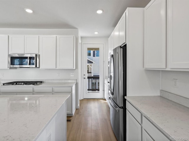 kitchen with white cabinets, light wood-type flooring, stainless steel appliances, and recessed lighting