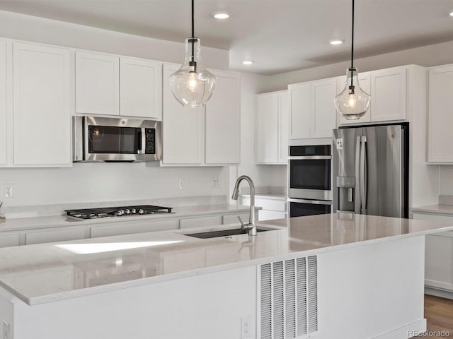 kitchen featuring recessed lighting, appliances with stainless steel finishes, white cabinetry, a sink, and an island with sink