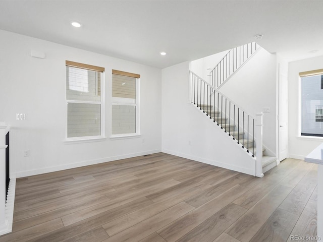 unfurnished living room featuring recessed lighting, stairway, baseboards, and wood finished floors