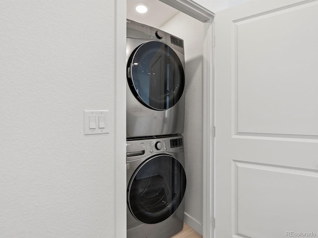 washroom with a textured wall, laundry area, and stacked washer / dryer
