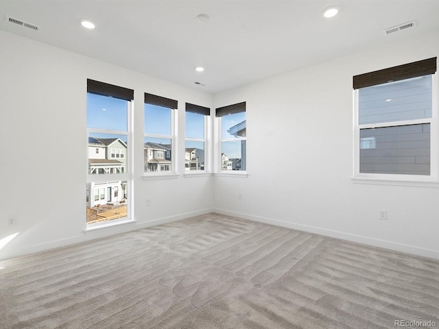 carpeted empty room featuring plenty of natural light, visible vents, and recessed lighting