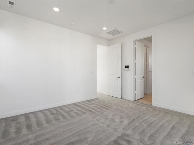 empty room featuring baseboards, visible vents, and recessed lighting