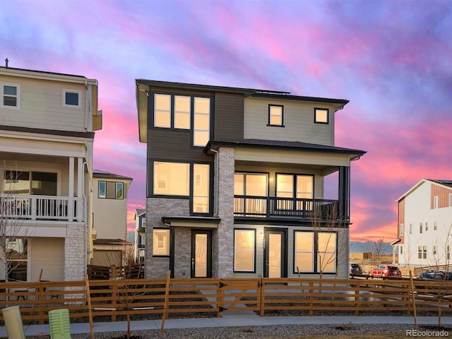 rear view of property with a fenced front yard and a balcony